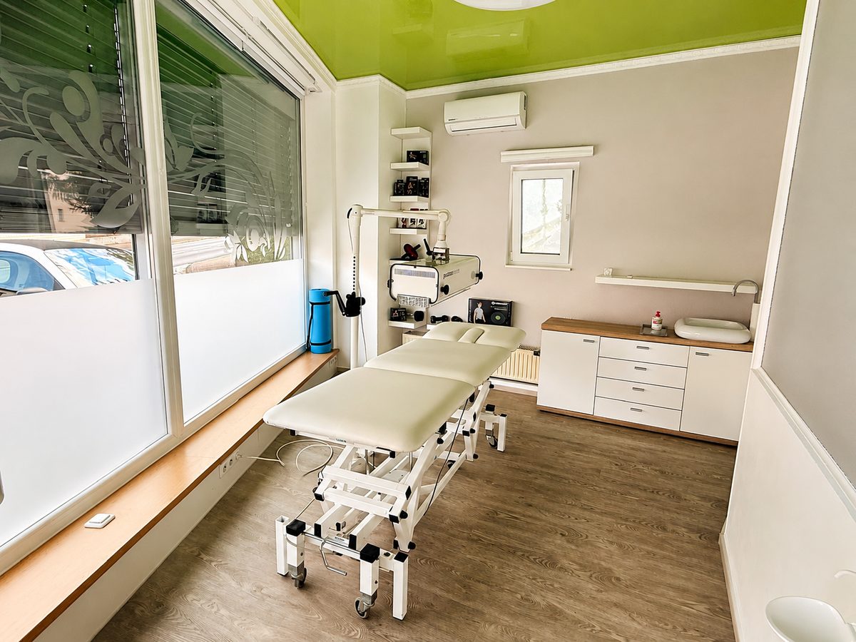 Behandlungsraum der Physiotherapie Mutić mit Liege, Schrank und Fenster zur Straße